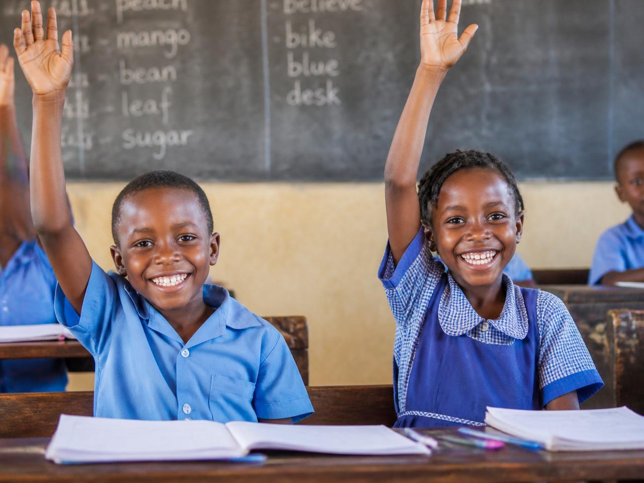 African schoolchildren raising their hands in class